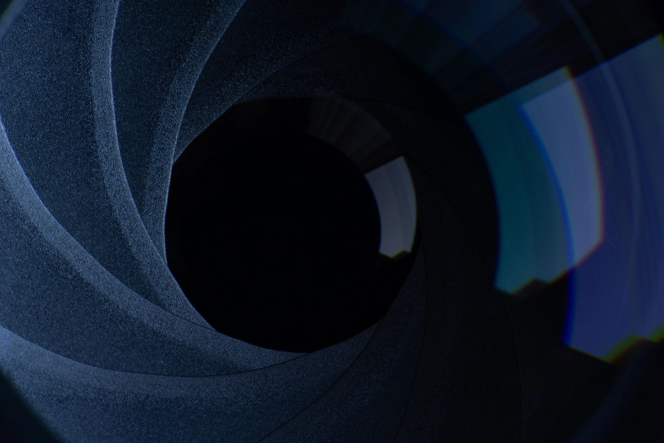 Macro close-up of a camera lens aperture in deep blue tones